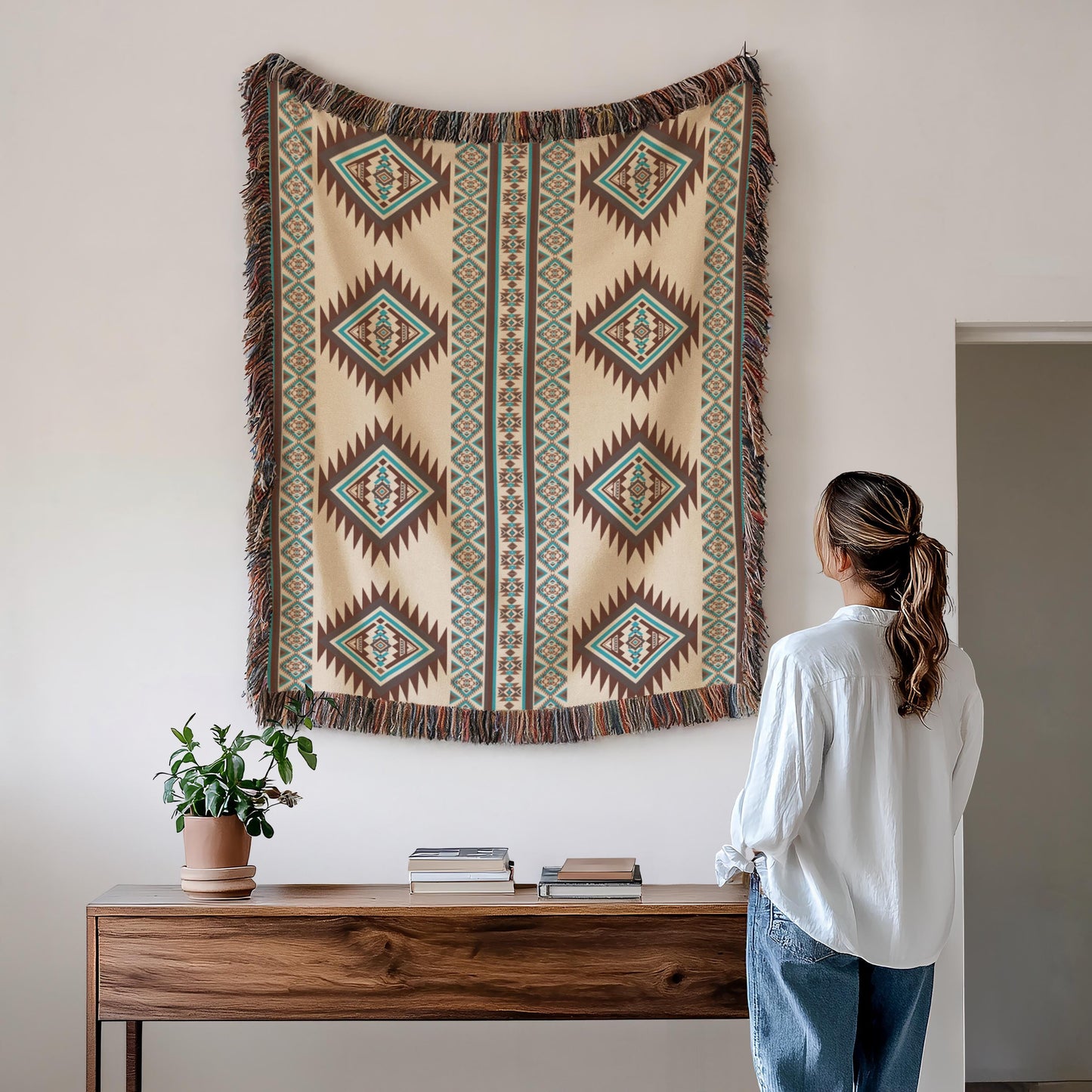 A woman stands in front of a wooden table, looking at a large, colorful tapestry hanging on the wall above it.