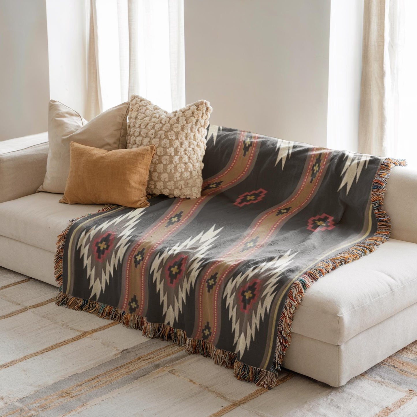 a cozy living room with a white sofa adorned with a patterned throw blanket and three decorative pillows.