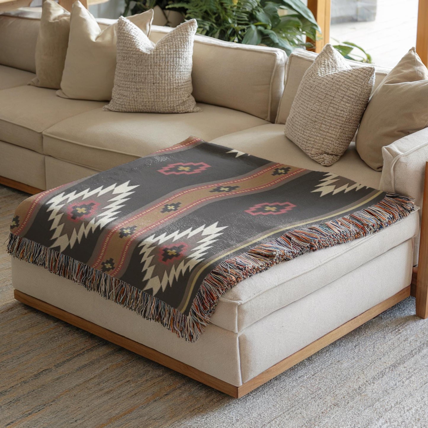 a cozy living room with a beige sofa and a decorative throw blanket on the ottoman.