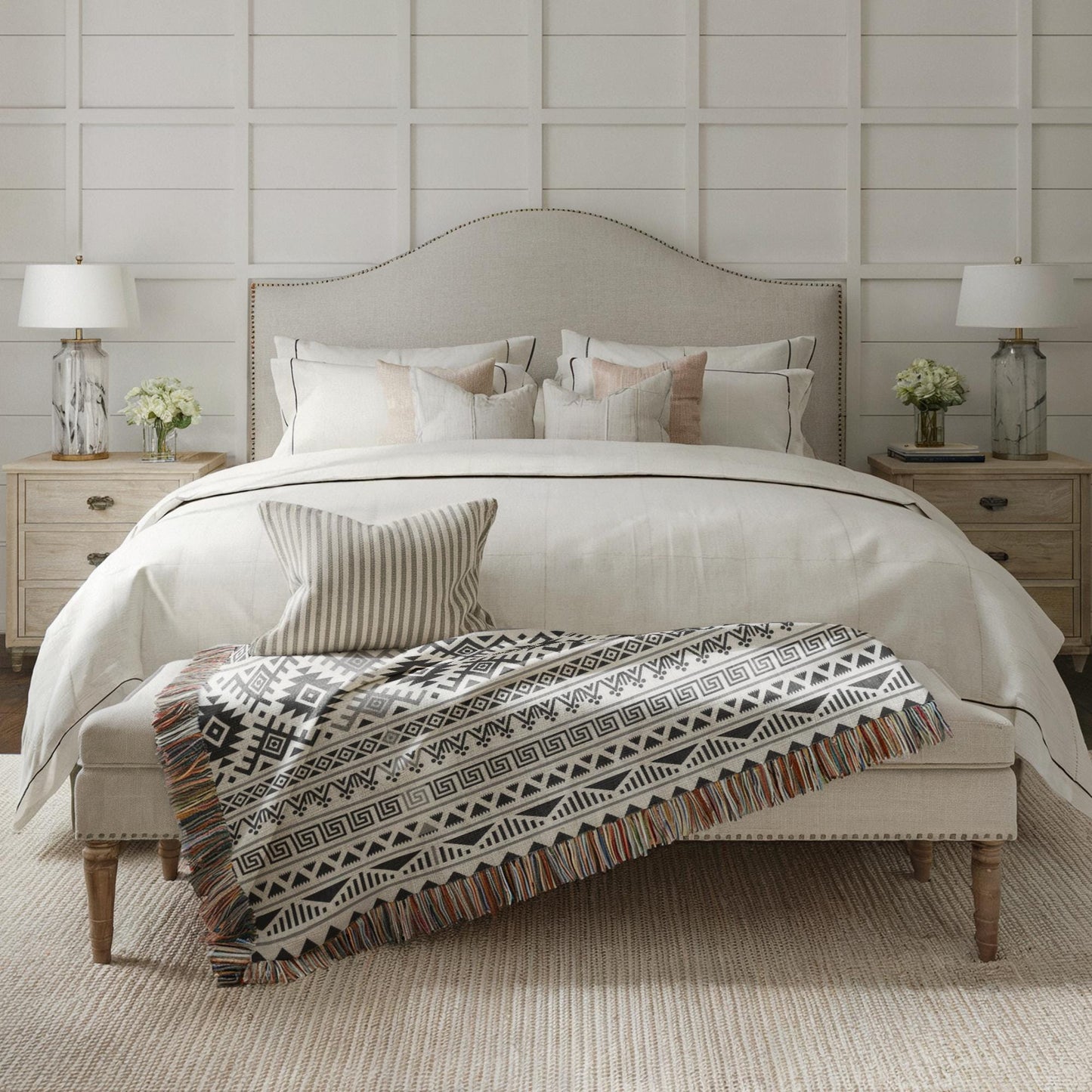 a well-decorated bedroom with a large bed, a wooden nightstand, and a patterned throw blanket.