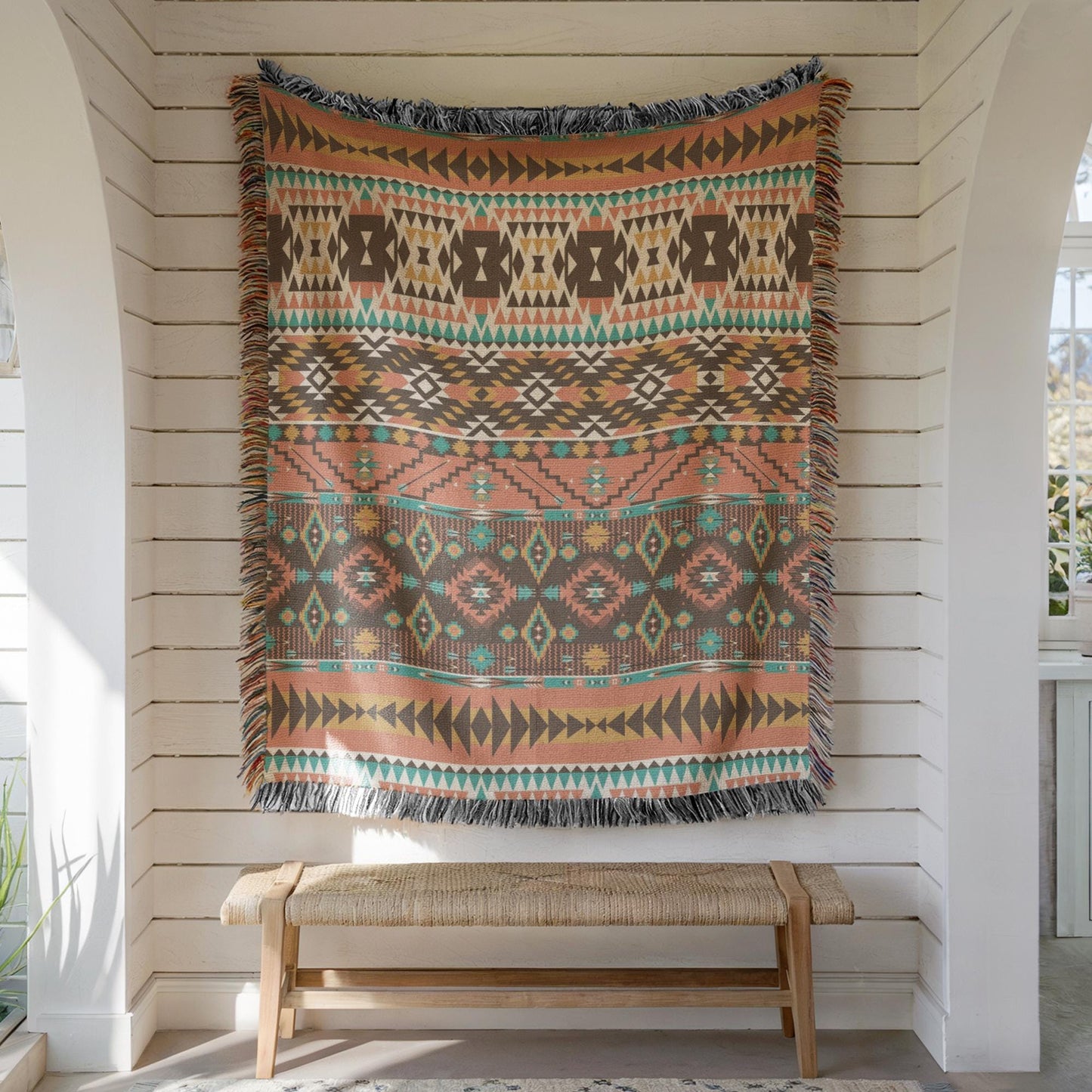 a large, colorful, patterned blanket hanging on a white wall, with a wooden bench below it.