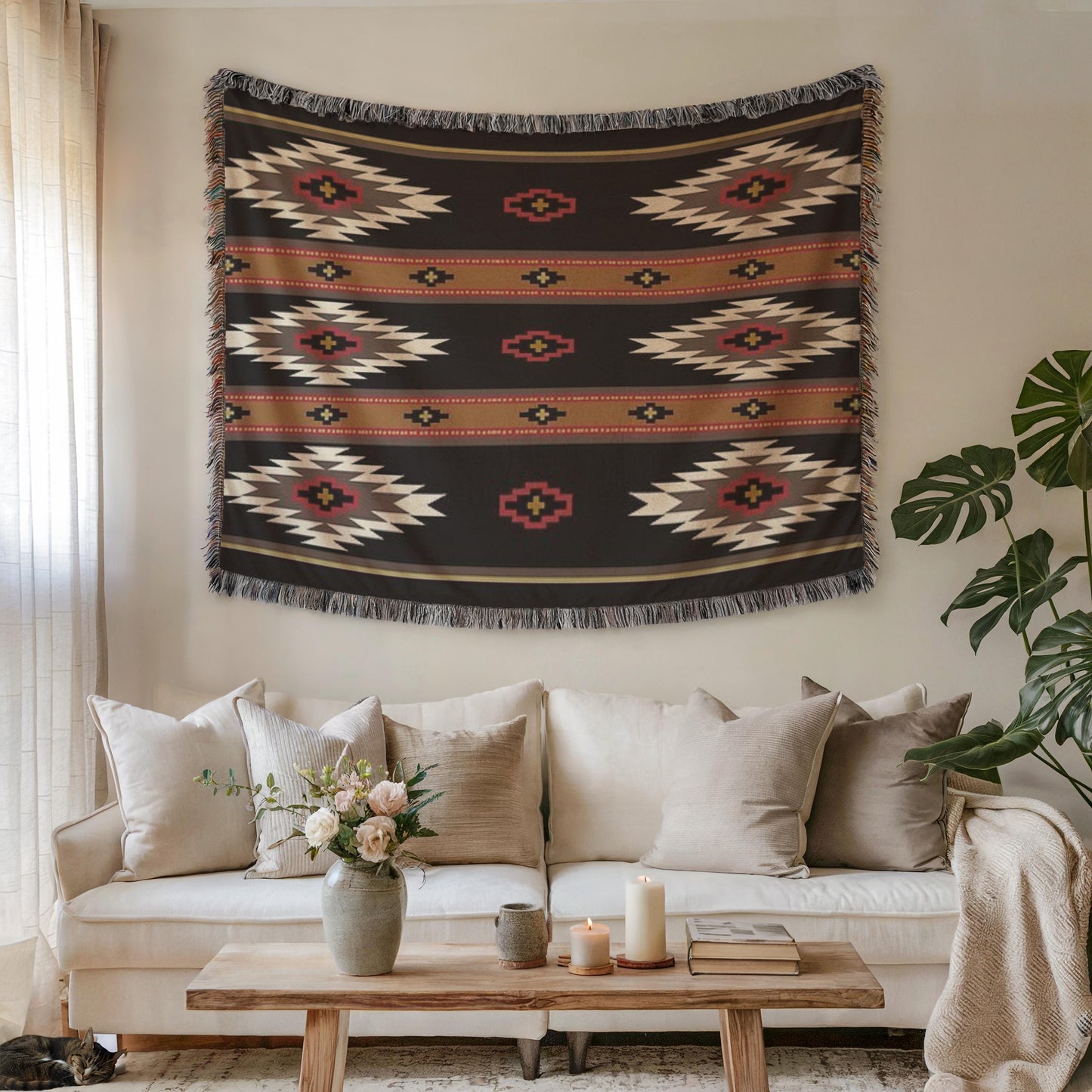 a cozy living room with a large, colorful, patterned tapestry hanging on the wall above a white sofa. The sofa is adorned with several throw pillows, and a wooden coffee table is placed in front of it. A vase of flowers and a book are also present on the coffee table, adding a touch of warmth and homeliness to the space.