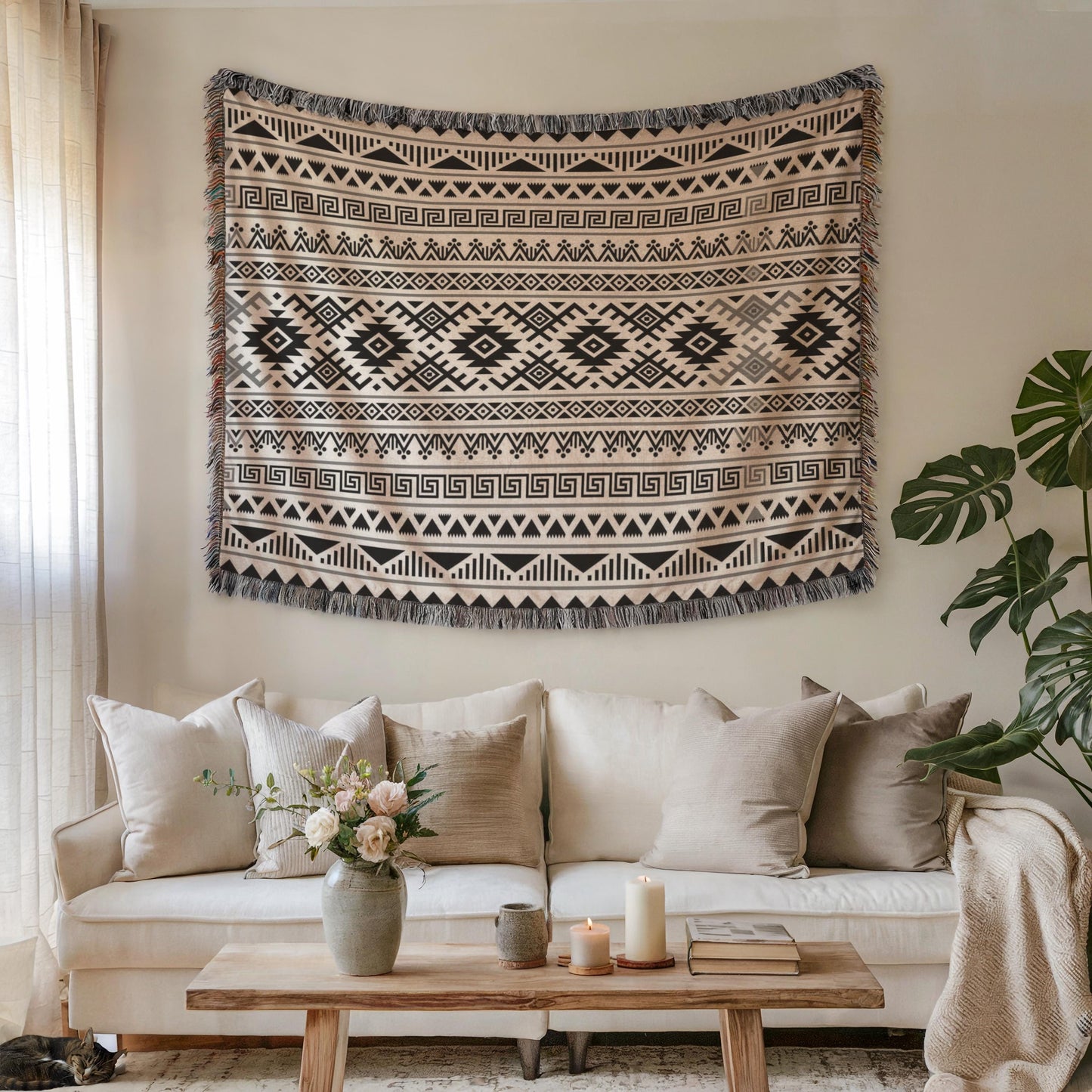 a cozy living room with a large, patterned tapestry hanging on the wall above a white sofa adorned with throw pillows. A wooden coffee table sits in front of the sofa, and a vase of flowers adds a touch of nature to the space. A potted plant is also present, contributing to the overall ambiance of the room.