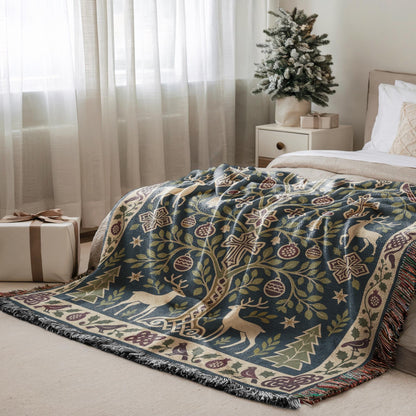 a cozy bedroom scene with a large, intricately patterned blanket featuring a tree design, a deer, and other festive elements. The blanket is draped over a bed, and a small Christmas tree is placed on a nightstand next to the bed. A gift box is also visible in the room, adding to the holiday atmosphere.