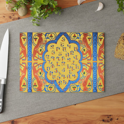 Yellow and blue Armenian alphabet cutting board on a grey mat beside a knife and fresh herbs