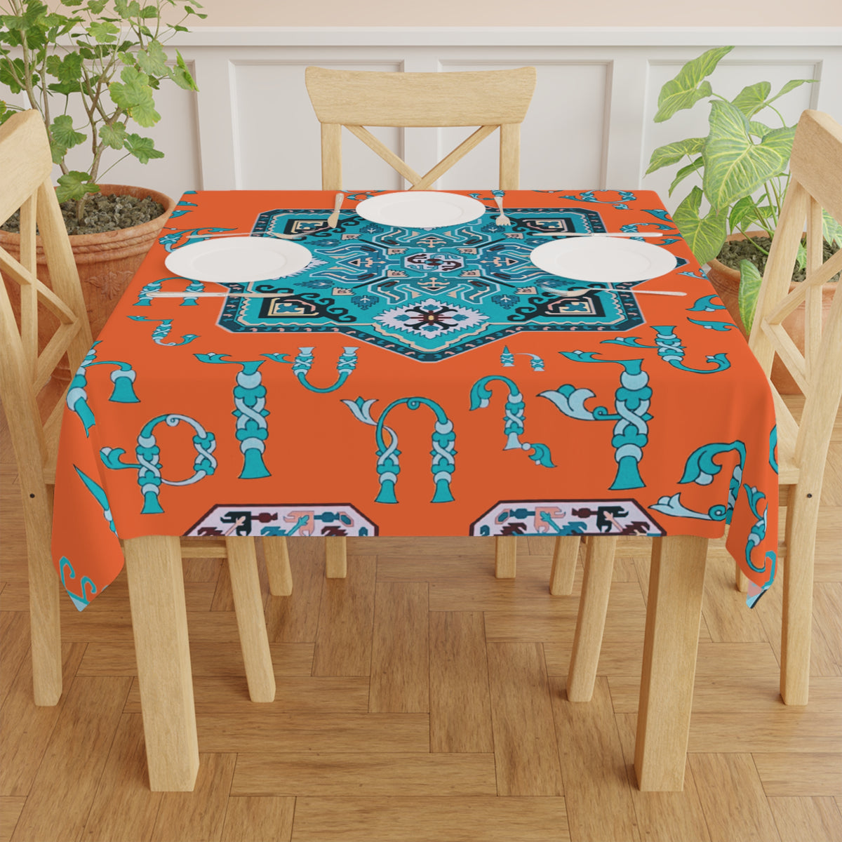 Orange and turquoise Armenian tablecloth on a round dining table with a vase and a bowl of fruit