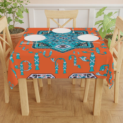 Orange and turquoise Armenian tablecloth on a round dining table with a vase and a bowl of fruit