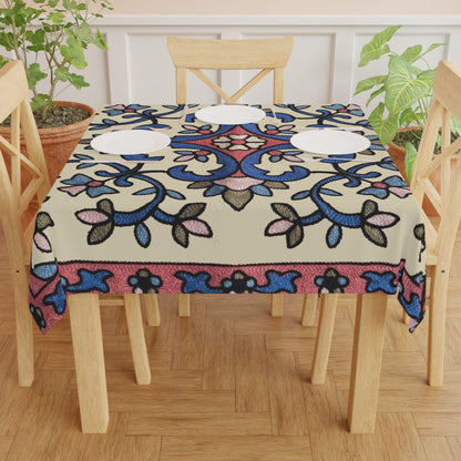 Cream Armenian floral tablecloth on a round dining table with a vase and a bowl of fruit