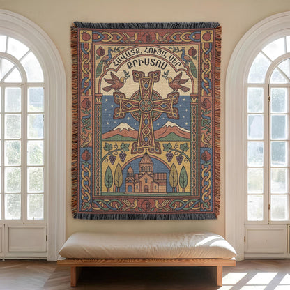 Woven Armenian cross wall hanging centred between two arched windows, cushioned bench below