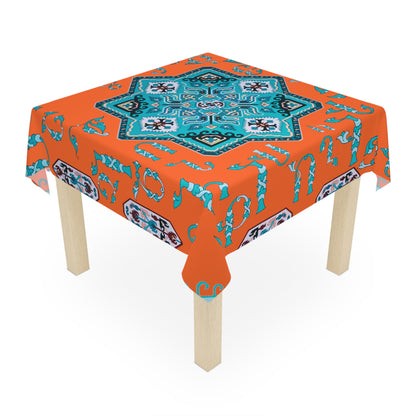 Orange and turquoise Armenian tablecloth on a rectangular table with wooden chairs and house plants