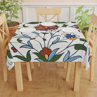 Blue and red Armenian pottery tablecloth on a round dining table with a vase and a bowl of fruit