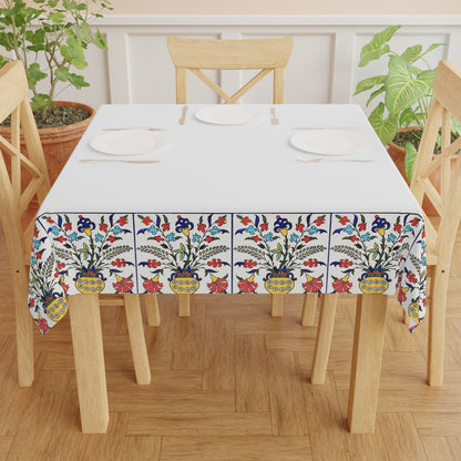 White Armenian tablecloth with floral border draped over a round table beside a window