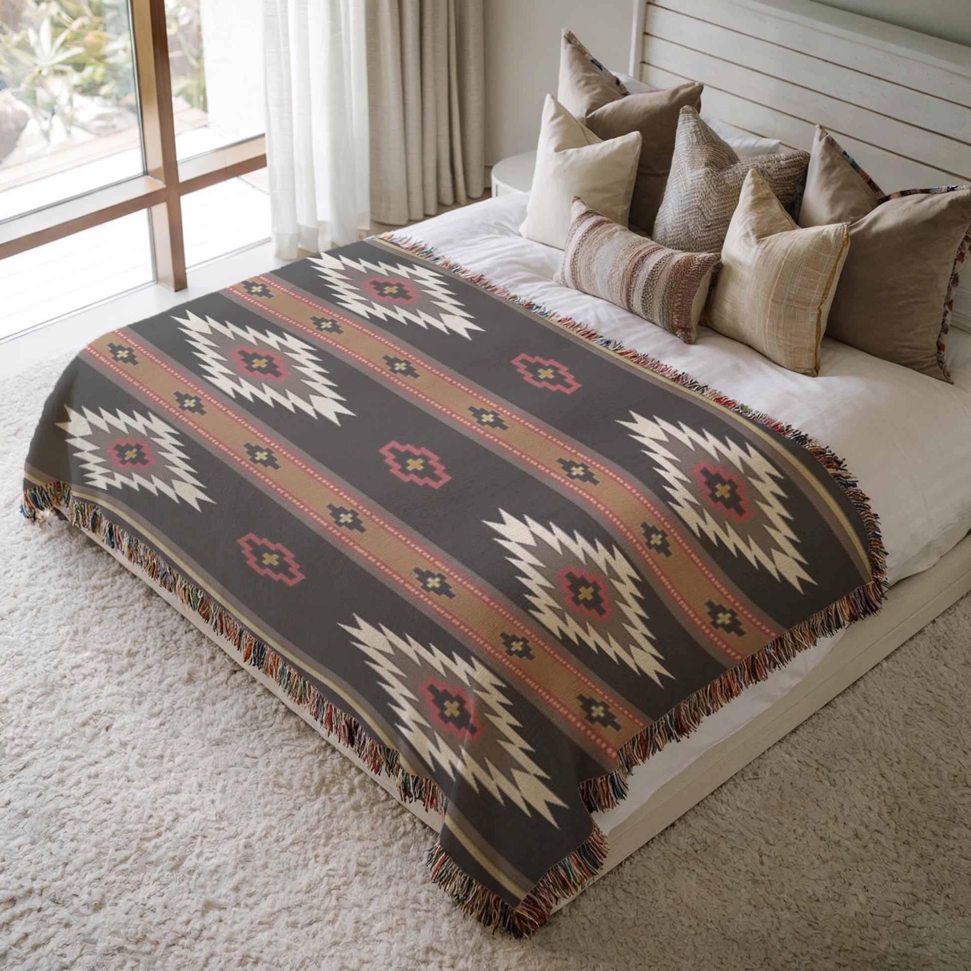 a cozy bedroom scene with a large bed covered in a patterned blanket and surrounded by multiple pillows. The bed is positioned against a wall with a window, creating a warm and inviting atmosphere.