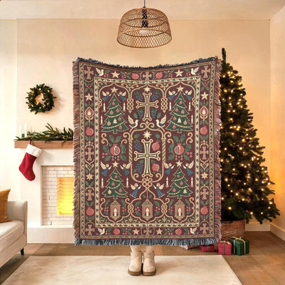 Armenian Christmas woven cotton blanket with fringe. A large Armenian-style cross anchors a burgundy field, surrounded by green Christmas trees, pomegranates, small church motifs and an ornamental border in muted gold and cream.