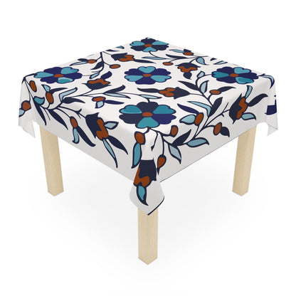 Blue and teal Armenian tablecloth on a round dining table with a vase and a bowl of fruit