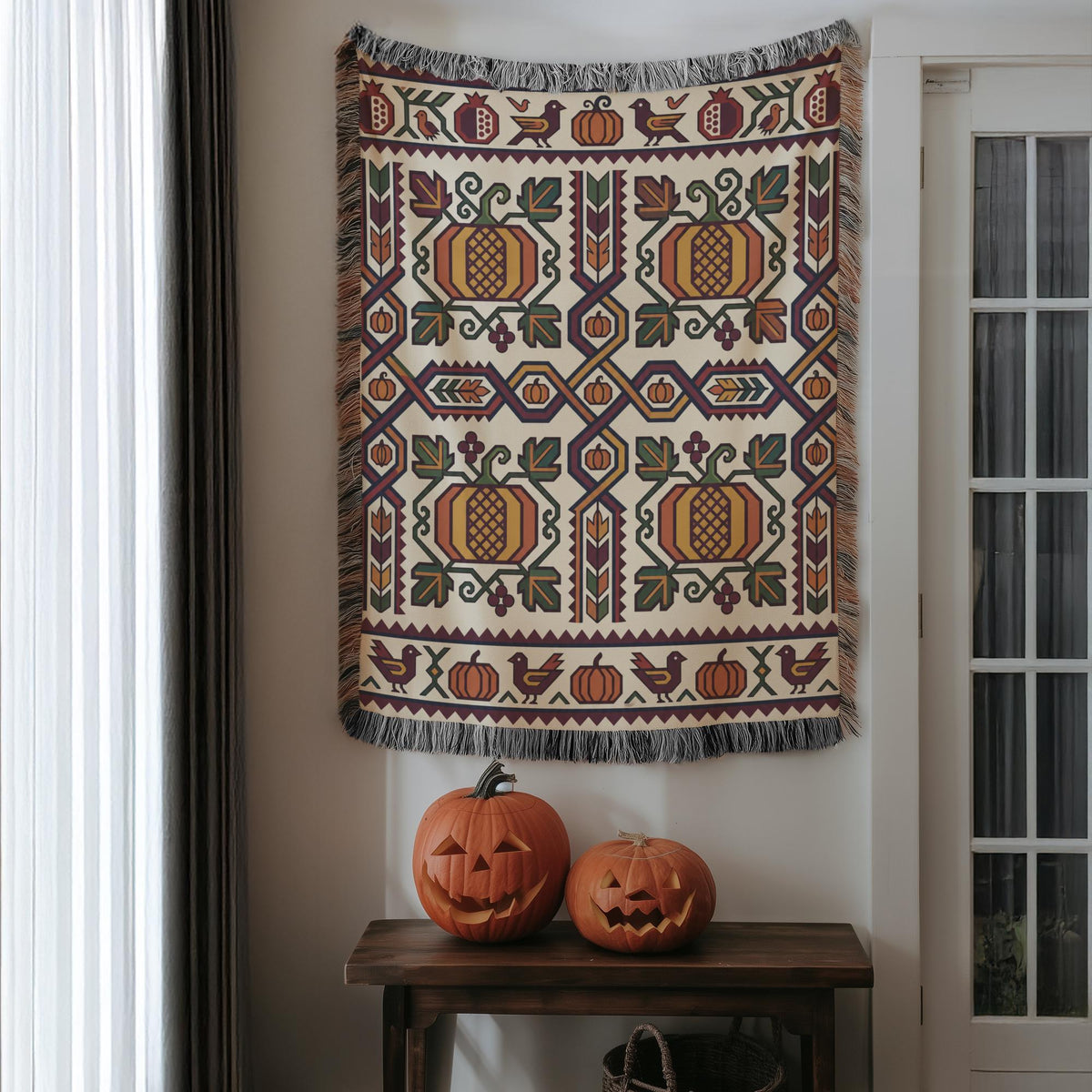 Geometric Ghapama woven blanket hung on a wall above two carved pumpkins