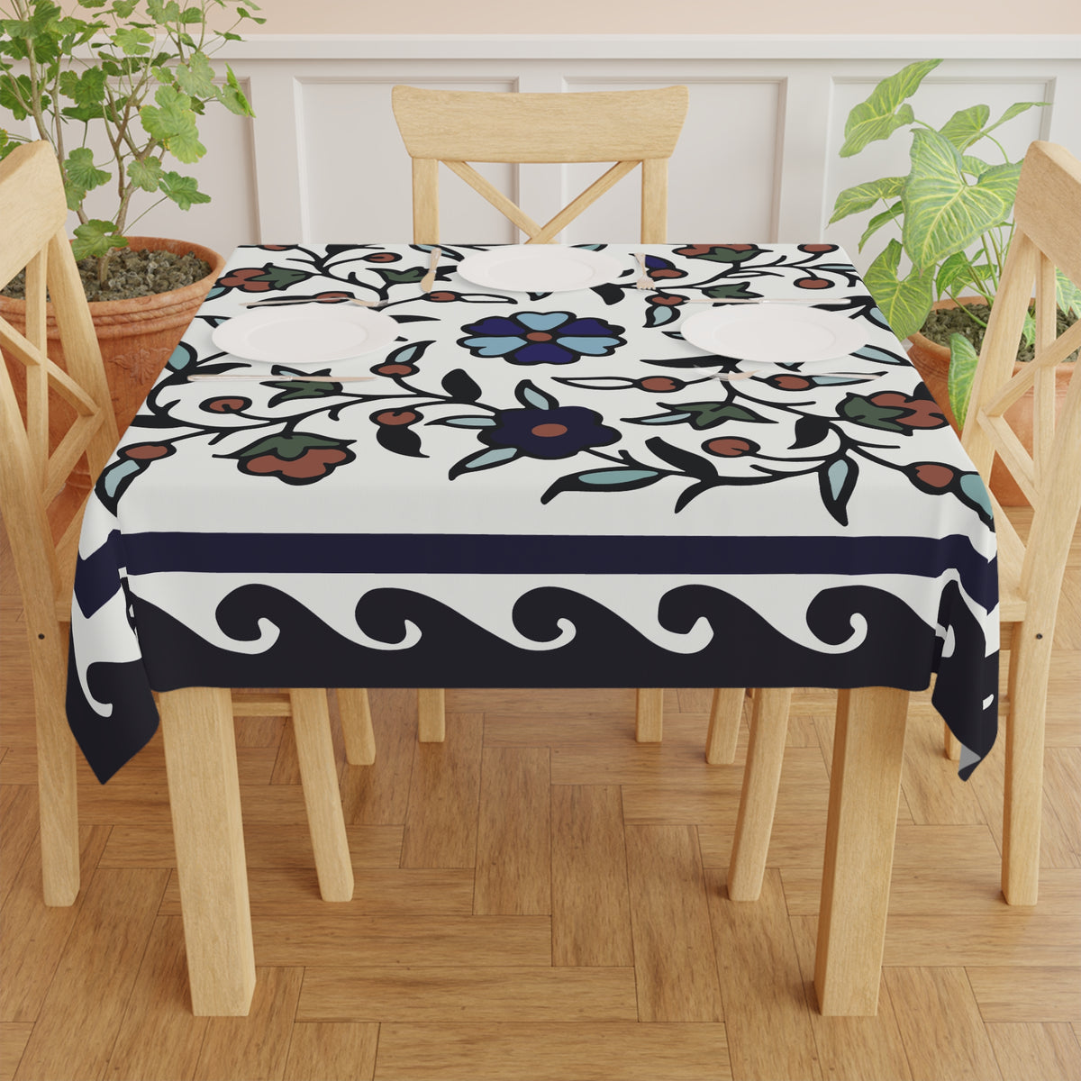 Navy bordered Armenian tablecloth on a round dining table with a vase and a bowl of fruit