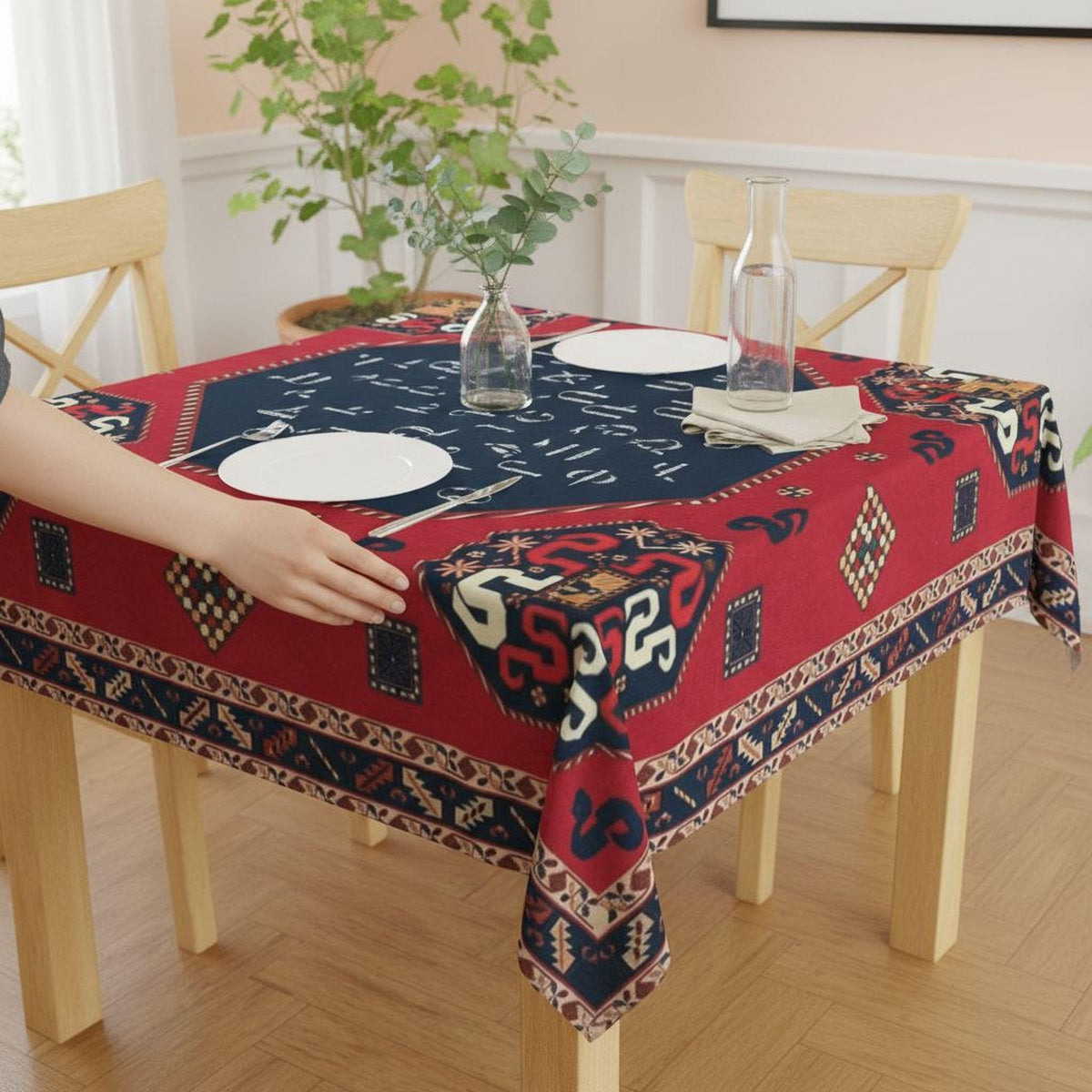 Armenian letters square tablecloth in navy and red on a dining table with a hand reaching for a plate