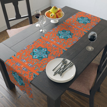 Orange and turquoise Armenian alphabet table runner on a dining table with wooden chairs and a bowl of fruit