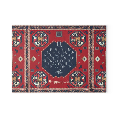 Red Armenian carpet cutting board with a family name on a grey mat beside a knife and fresh herbs
