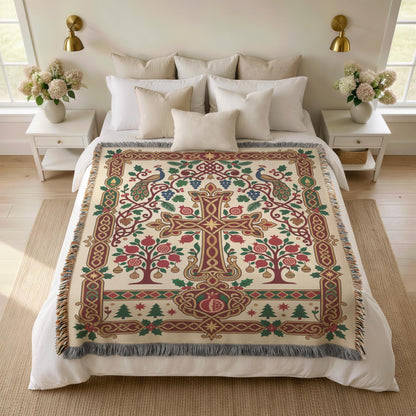 Armenian Christmas woven cotton blanket with fringe. A central ornamental cross stands between branching pomegranate trees on a cream background. Red fruit, green leaves, small Christmas trees and a burgundy-and-gold border create a lighter festive palette.