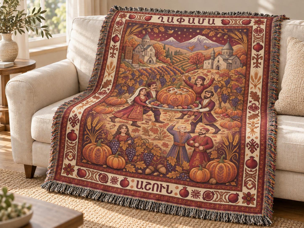 Armenian Ghapama woven cotton blanket draped over a couch, showing a family carrying a stuffed pumpkin, village mountains and a muted burgundy harvest border.