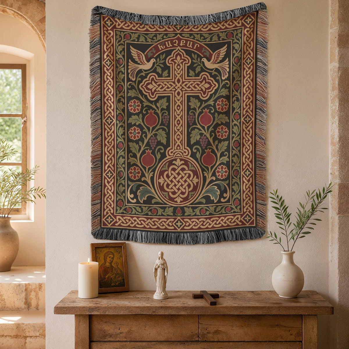 Khachkar tapestry with doves and pomegranates on a plaster wall beside an arched window and potted plants