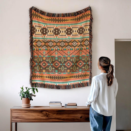 A woman stands in front of a wooden table, looking up at a large, colorful, patterned tapestry hanging on the wall above the table.
