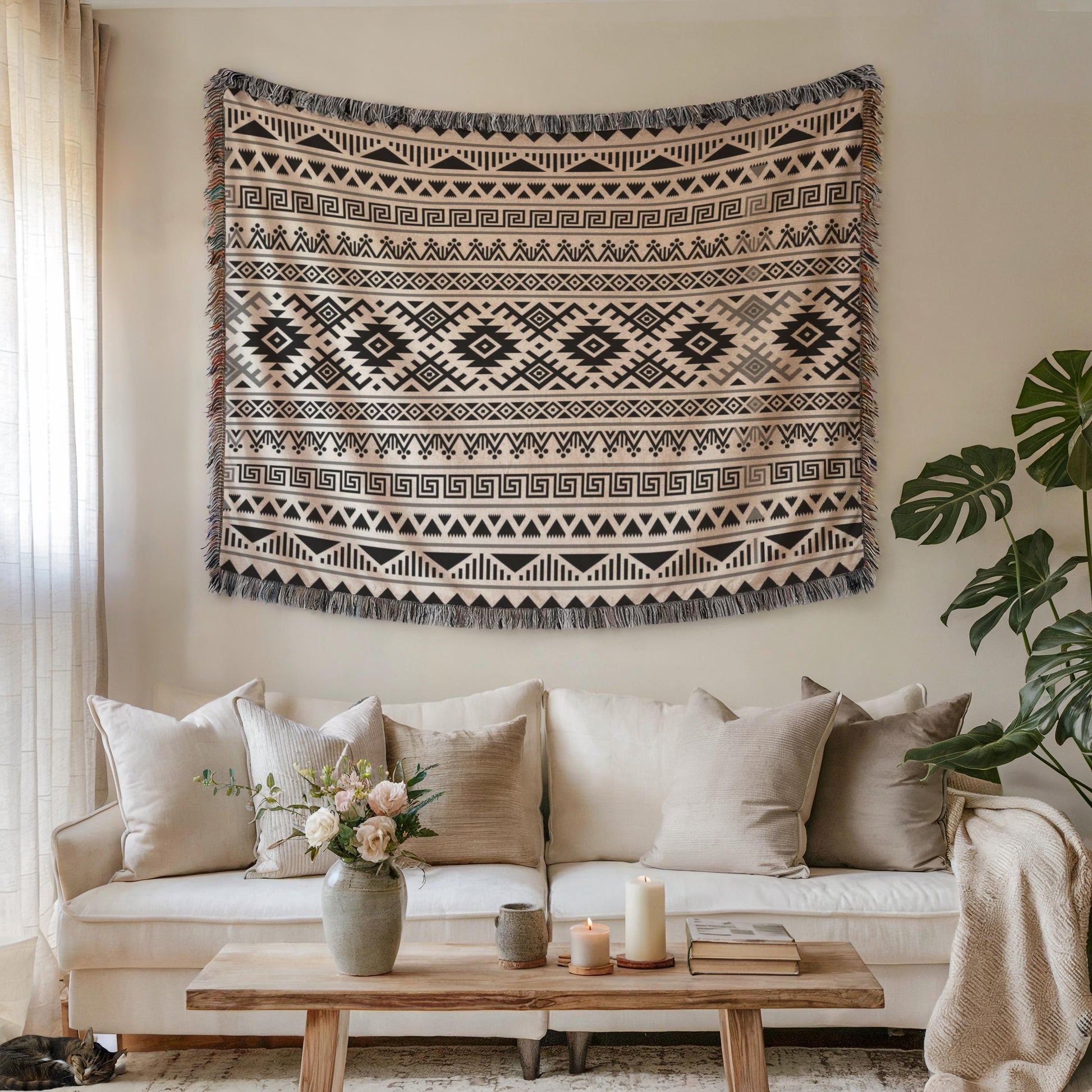 a cozy living room with a large, patterned tapestry hanging on the wall above a white sofa adorned with throw pillows. A wooden coffee table sits in front of the sofa, and a vase of flowers adds a touch of nature to the space. A potted plant is also present, contributing to the overall ambiance of the room.