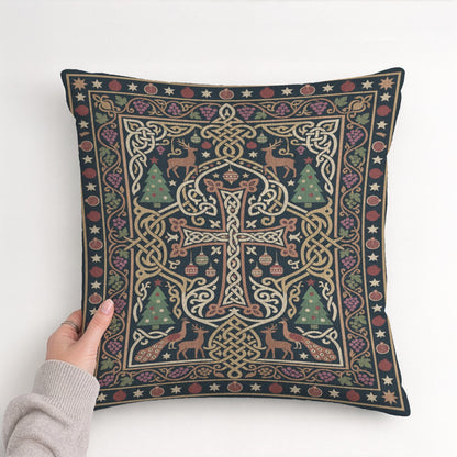 A hand is holding up a decorative pillow with an intricate, colorful design featuring a cross, Christmas trees, and other festive elements.