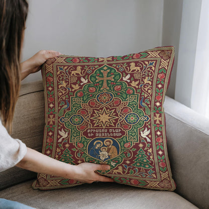 A person is holding a decorative pillow with an ornate, colorful design featuring religious imagery and text.