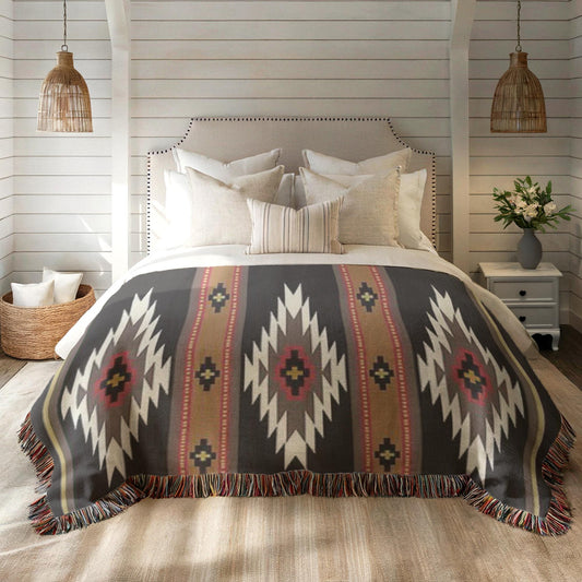 a cozy bedroom with a large bed adorned with a colorful, patterned blanket and pillows. The bed is set against a backdrop of white walls and wooden beams, creating a warm and inviting atmosphere. The room also includes a nightstand with a vase of flowers, adding a touch of nature and elegance to the space.
