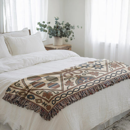Rust and teal geometric throw folded across a white bed beside a sunlit window
