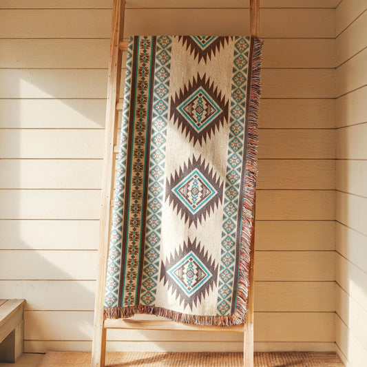 A colorful, patterned blanket is draped over a wooden ladder against a white wall.