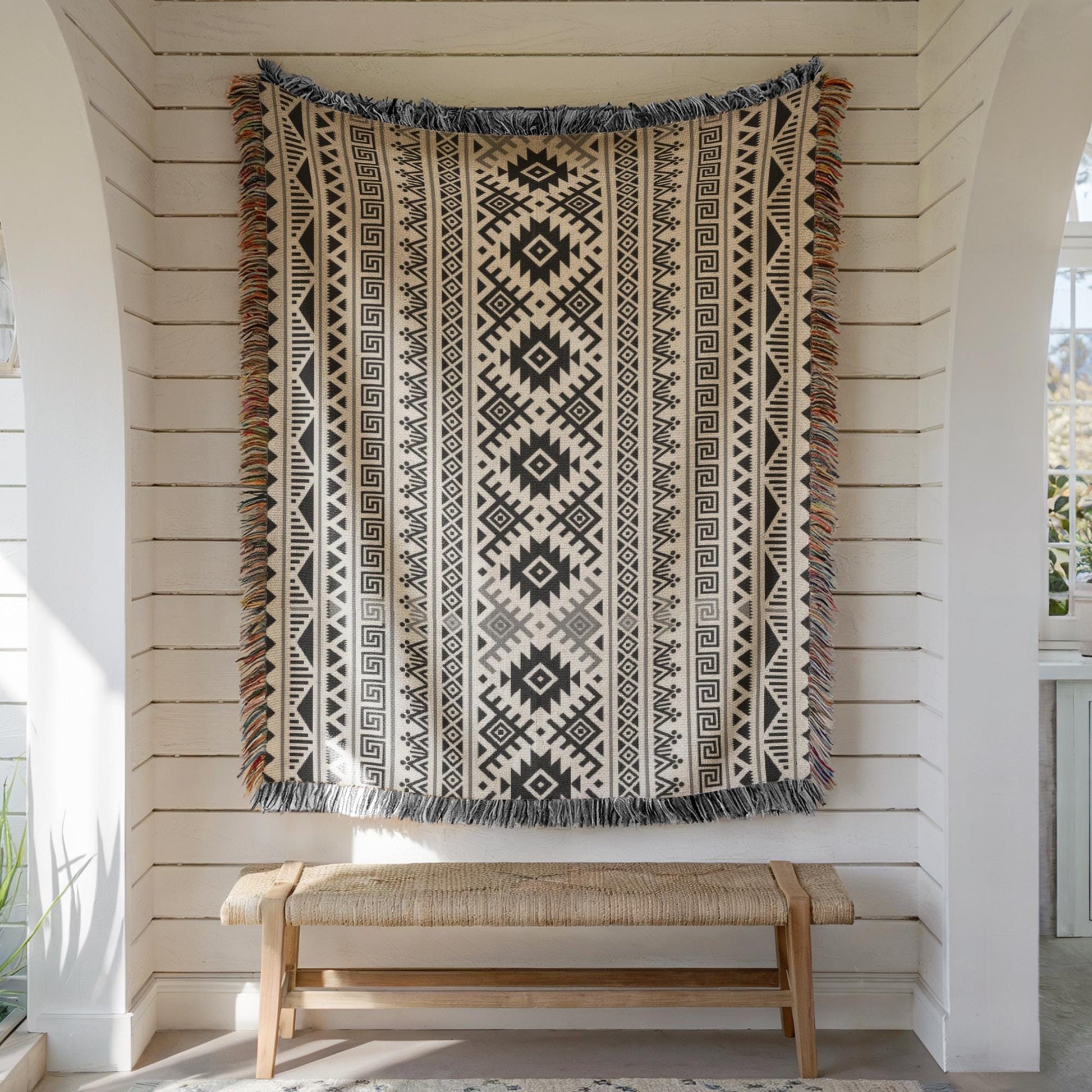 a large, intricately patterned rug hanging on a white wall, with a wooden bench below it.