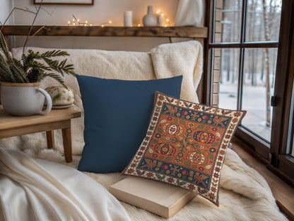 The patterned pumpkin pillow shown beside the plain navy option on a bench by a winter window
