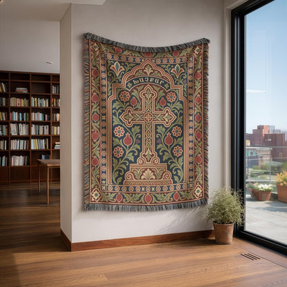 Khachkar cross tapestry in a pointed arch on a white wall beside bookshelves and a tall window